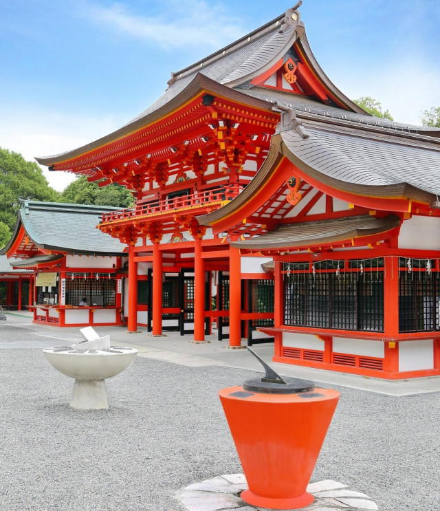 近江神宮の朱塗りの楼門と社殿。青空の下、鮮やかな朱色と白壁が美しく映える境内の景観。