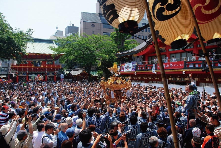 神田明神の境内で、大勢の担ぎ手たちが神輿を担ぎ上げる神田祭の様子