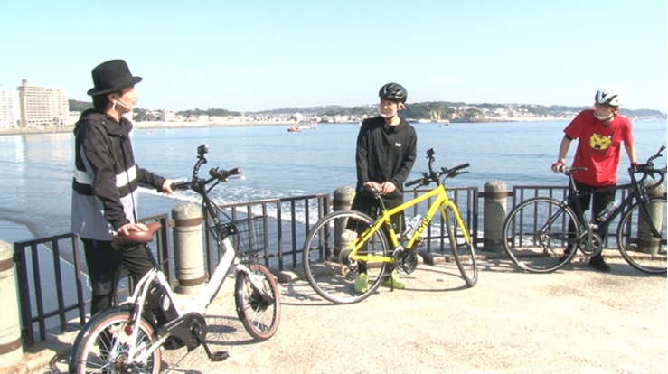 江ノ島の海辺で自転車に乗る山下大輝さん、鳥海浩輔さん、福島潤さん。ミニベロ、クロスバイク、ロードバイクで並ぶ姿。