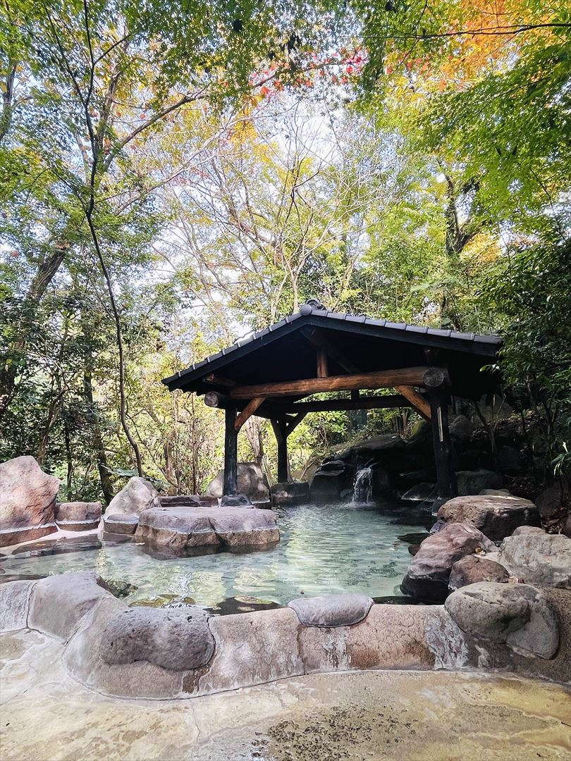 玉名温泉の自然豊かな露天風呂。紅葉に囲まれた岩風呂と湯煙の風景